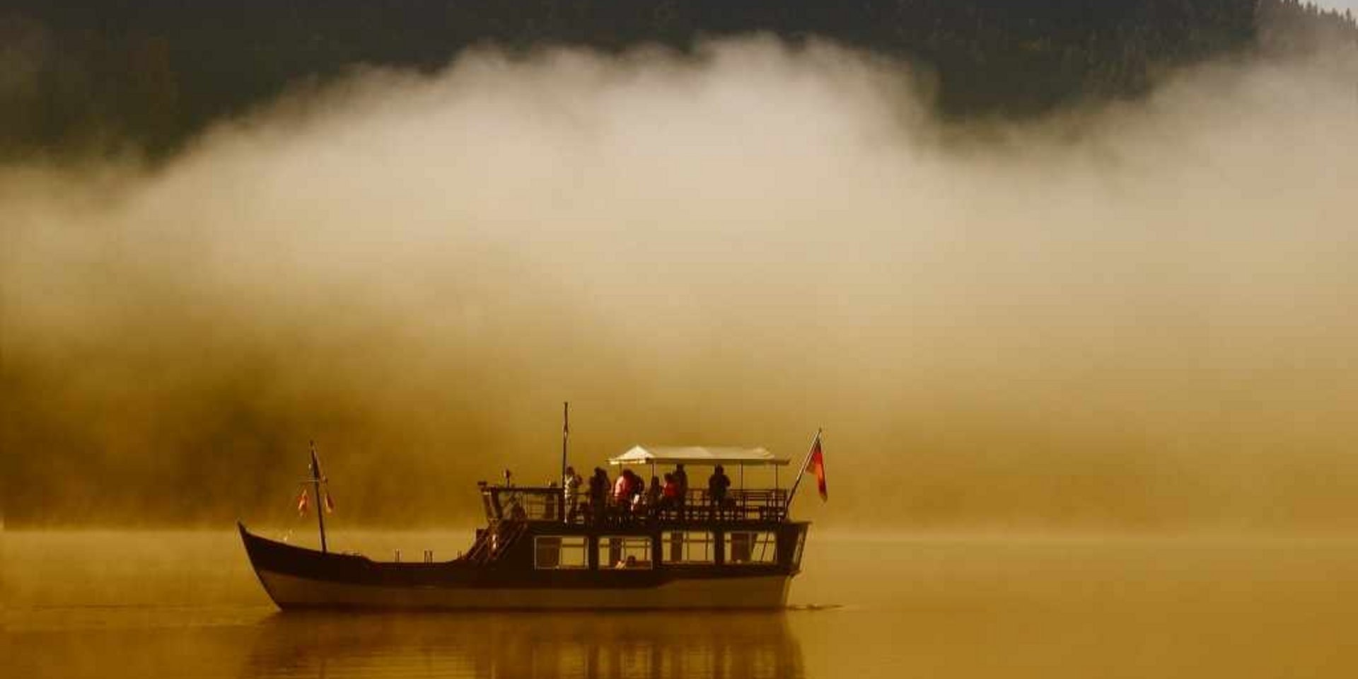 Ein kleines Boot auf einem nebligen Schwarzwaldsee in der Morgendämmerung.