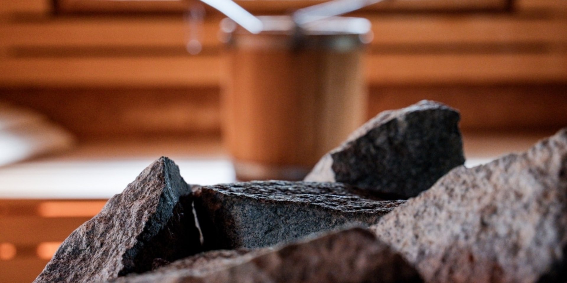 Rustikale Dekoration mit Holzscheiten und einer Schale im gemütlichen Wellnessbereich des Hotels Vier Jahreszeiten.