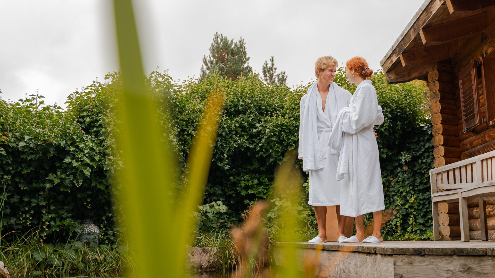 Zwei Gäste in Bademänteln genießen die frische Schwarzwaldluft auf der Terrasse des Wellnessbereichs.