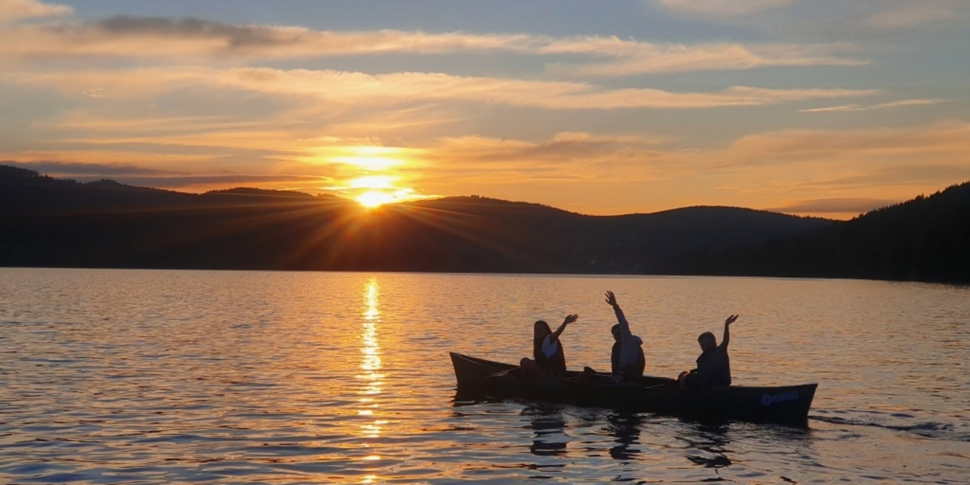 Romantischer Sonnenuntergang über dem Schluchsee im Schwarzwald mit einem kleinen Boot auf dem Wasser.