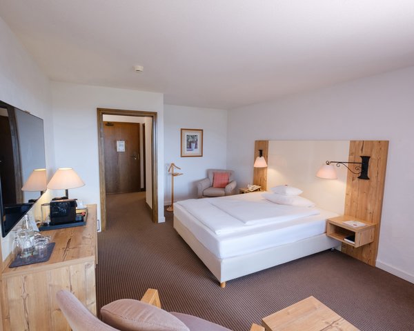 Blick in das großzügige Einzelzimmer Komfort Süd mit gemütlichem Sessel und TV-Bereich.