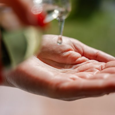 Nahaufnahme von Massageöl, das in die Handflächen einer Masseurin im Hotel Vier Jahreszeiten im Schwarzwald fließt.