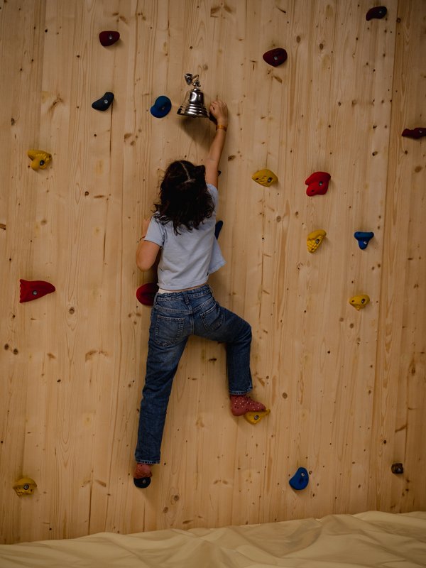 Ein Kind erklimmt mutig die Kletterwand in der Spielwelt des Hotels Vier Jahreszeiten im Schwarzwald.