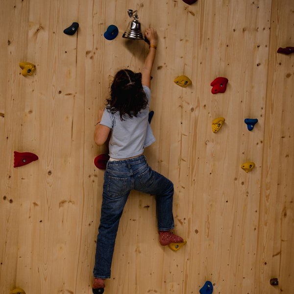 Ein Kind erklimmt mutig die Kletterwand in der Spielwelt des Hotels Vier Jahreszeiten im Schwarzwald.