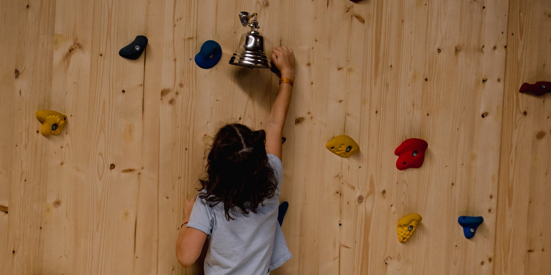 Ein Kind erklimmt mutig die Kletterwand in der Spielwelt des Hotels Vier Jahreszeiten im Schwarzwald.