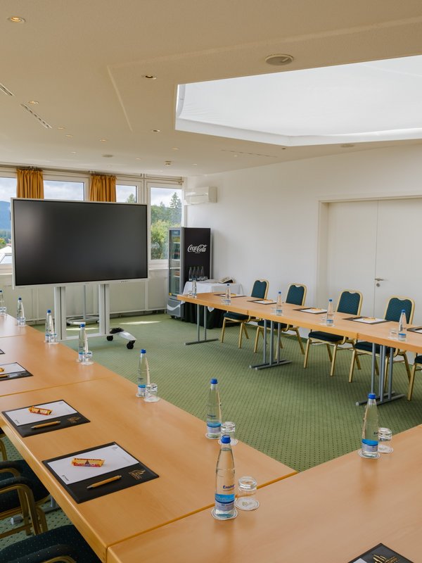 Professionelle Konferenz-Umgebung mit großem Präsentationsbildschirm und Blick in die Schwarzwaldlandschaft im Hotel Vier Jahreszeiten.