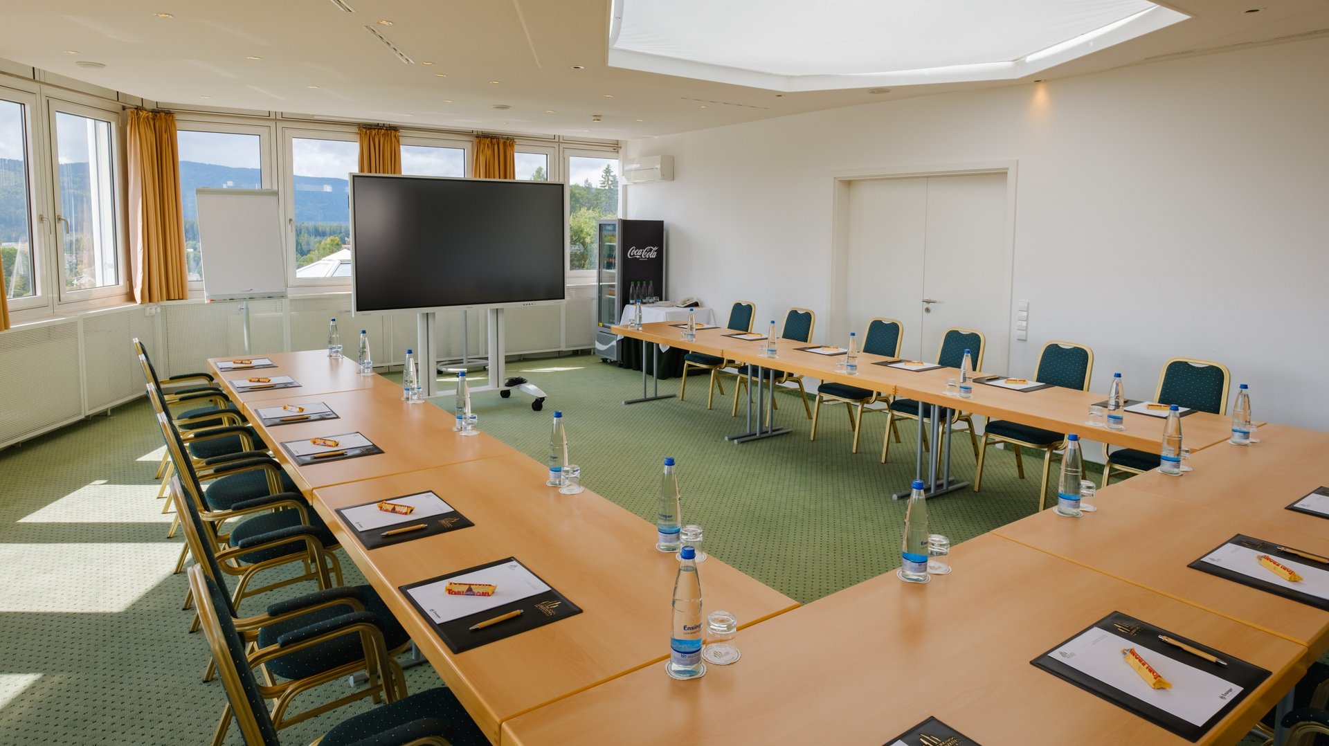 Professionelle Konferenz-Umgebung mit großem Präsentationsbildschirm und Blick in die Schwarzwaldlandschaft im Hotel Vier Jahreszeiten.