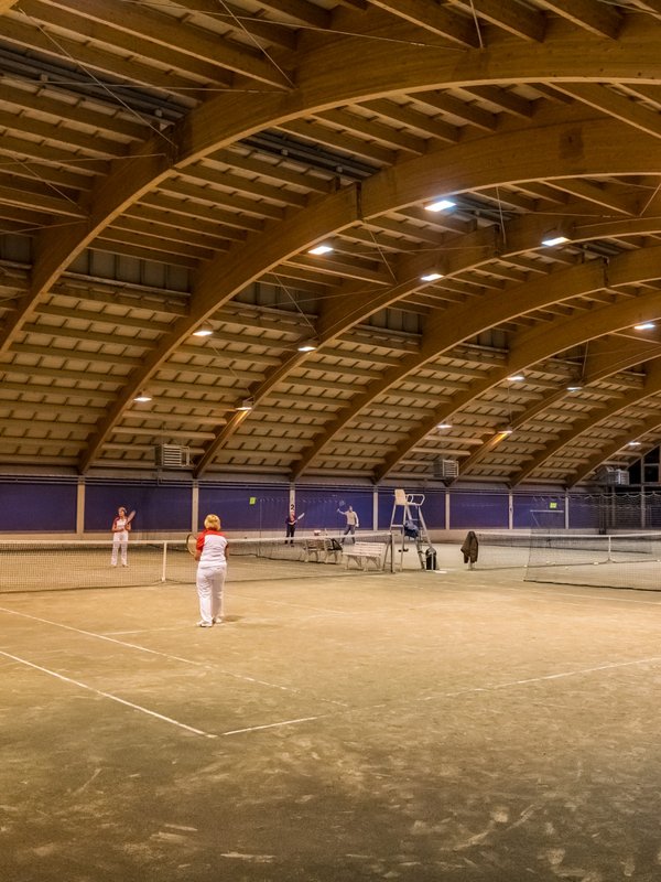 Tennishalle mit mehreren Plätzen und Spielern