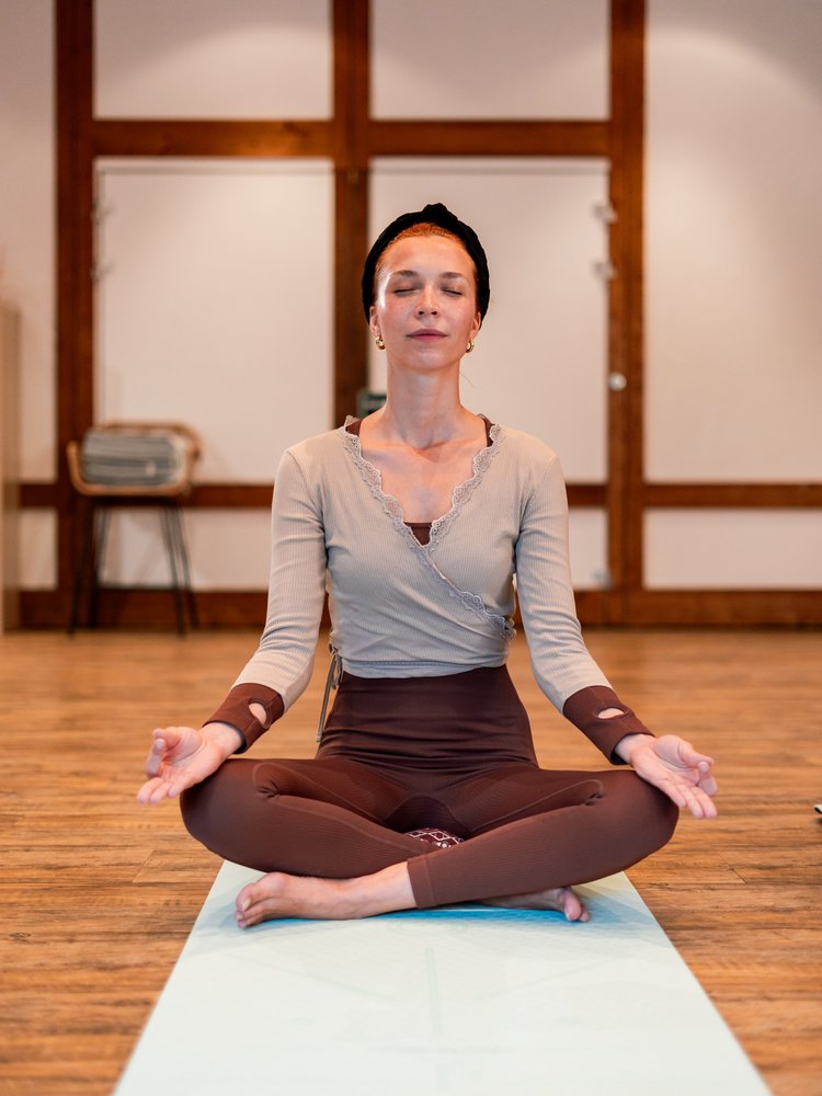 Eine Frau in Meditationshaltung auf einer Yoga-Matte im hellen Kursraum des Hotels Vier Jahreszeiten am Schluchsee.