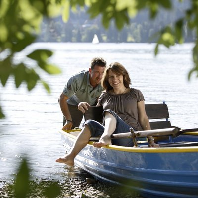 Ein Paar genießt eine ruhige Fahrt in einem blauen Ruderboot auf dem Schluchsee.