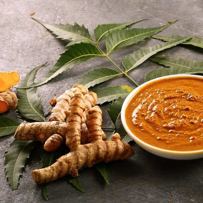 Eine Paste neben ganzen Stücken von Kurkuma