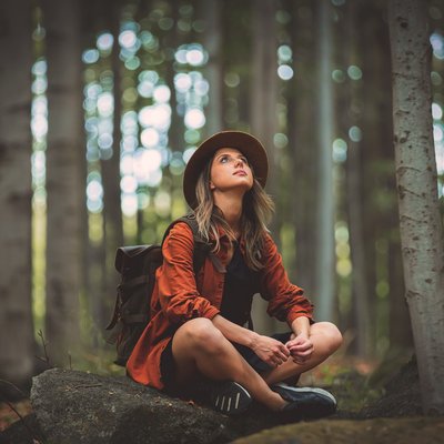 Frau sitzt im Wald auf einem Stein