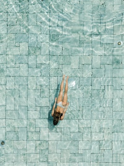 Eine Schwimmerin zieht ihre Bahnen im weitläufigen und hell erleuchteten Pool.