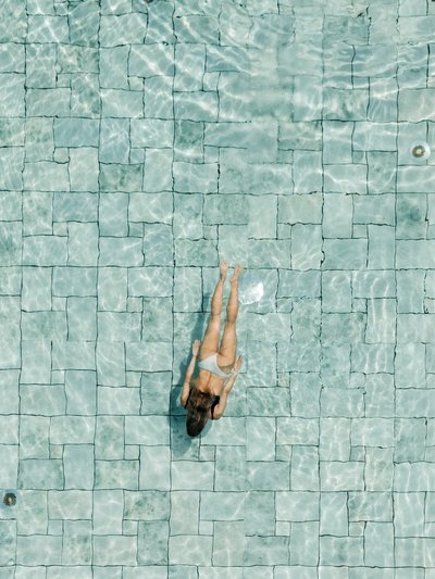 Eine Schwimmerin zieht ihre Bahnen im weitläufigen und hell erleuchteten Pool.