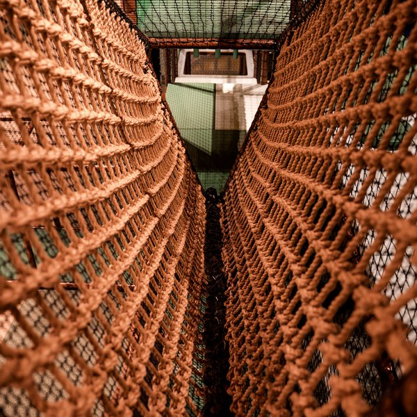 Blick durch die Seilkonstruktionen eines Klettertunnels in der Abenteuerwelt des Hotels Vier Jahreszeiten im Schwarzwald.