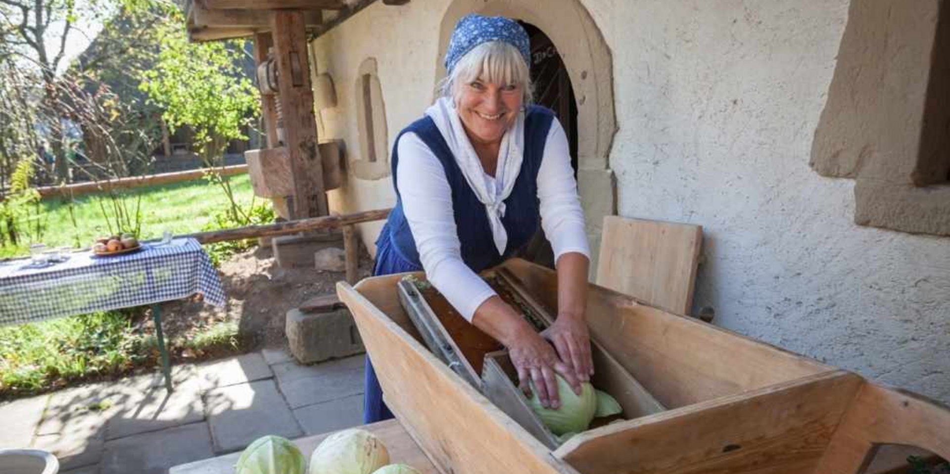 Eine Frau in historischer Kleidung bei der traditionellen Handarbeit (Weben/Waschen).