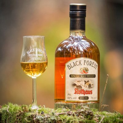 Eine Flasche Rothaus Black Forest Single Malt Whisky stilvoll in der Natur präsentiert.