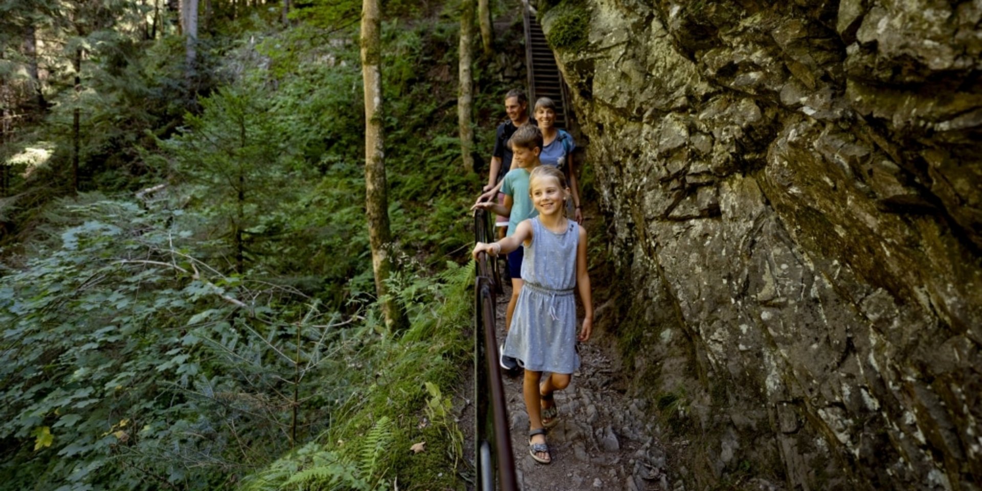Wanderer auf einem schmalen Pfad entlang markanter Felswände.
