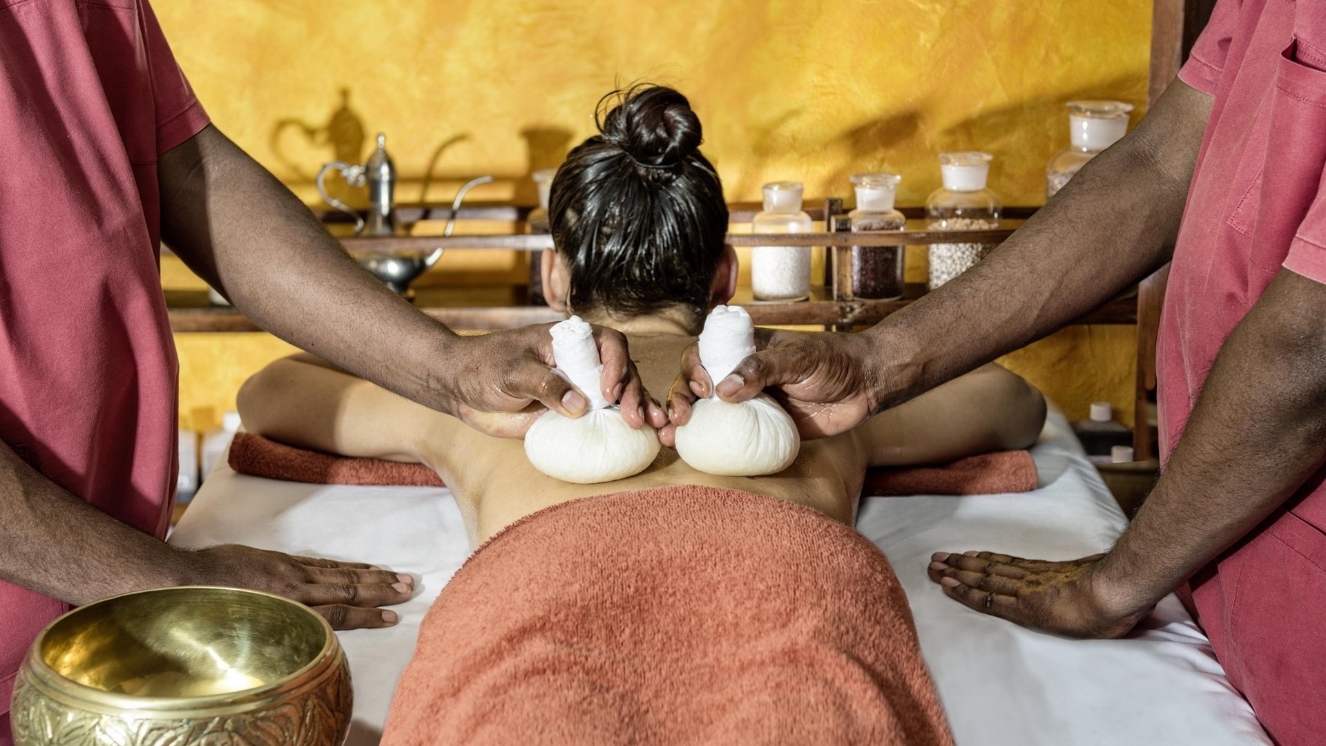 Zwei Therapeuten führen gleichzeitig eine ayurvedische Stempelmassage im Hotel Vier Jahreszeiten am Schluchsee durch.