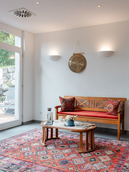 Einladender Wartebereich im Spa des Hotels Vier Jahreszeiten mit gemütlichem Sofa und orientalischem Teppich.