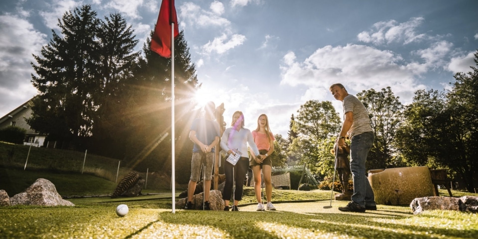 Gäste spielen eine Runde Minigolf im Abenteuer-Golfpark in der Nähe des Hotels Vier Jahreszeiten.