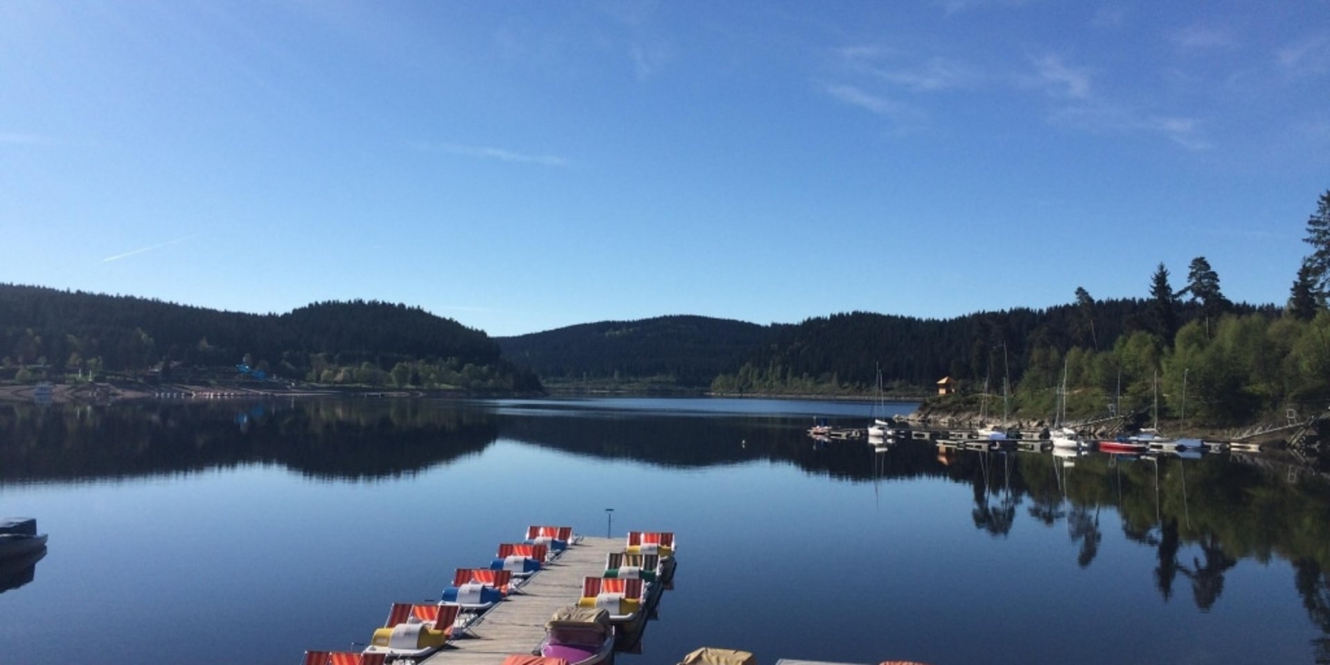 Ein langer Bootssteg am Schluchsee mit Blick auf die umliegenden bewaldeten Schwarzwaldberge.