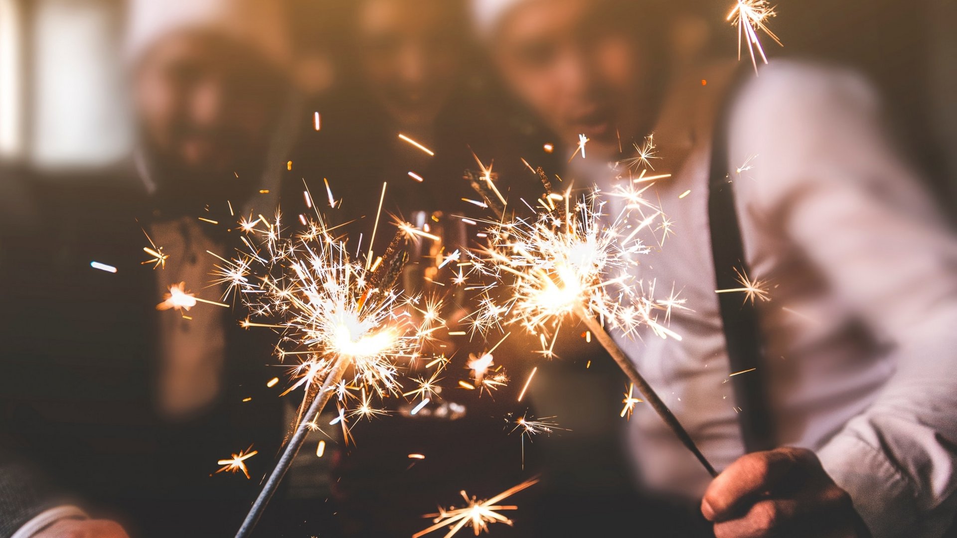 Menschen feiern mit Wunderkerzen und festlicher Stimmung eine Weihnachts- oder Silvesterparty.