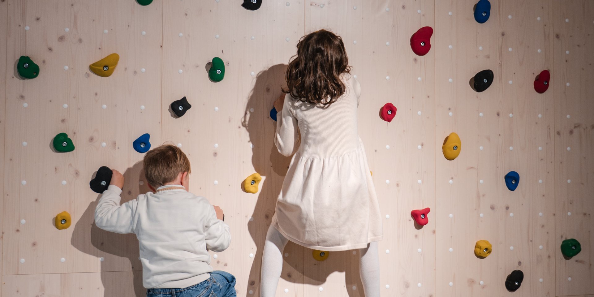 Zwei Kinder erklimmen gemeinsam die bunte Kletterwand in der Spielhalle des Hotels Vier Jahreszeiten am Schluchsee.