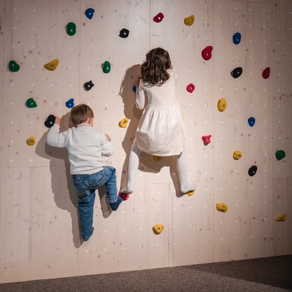 Zwei Kinder erklimmen gemeinsam die bunte Kletterwand in der Spielhalle des Hotels Vier Jahreszeiten am Schluchsee.