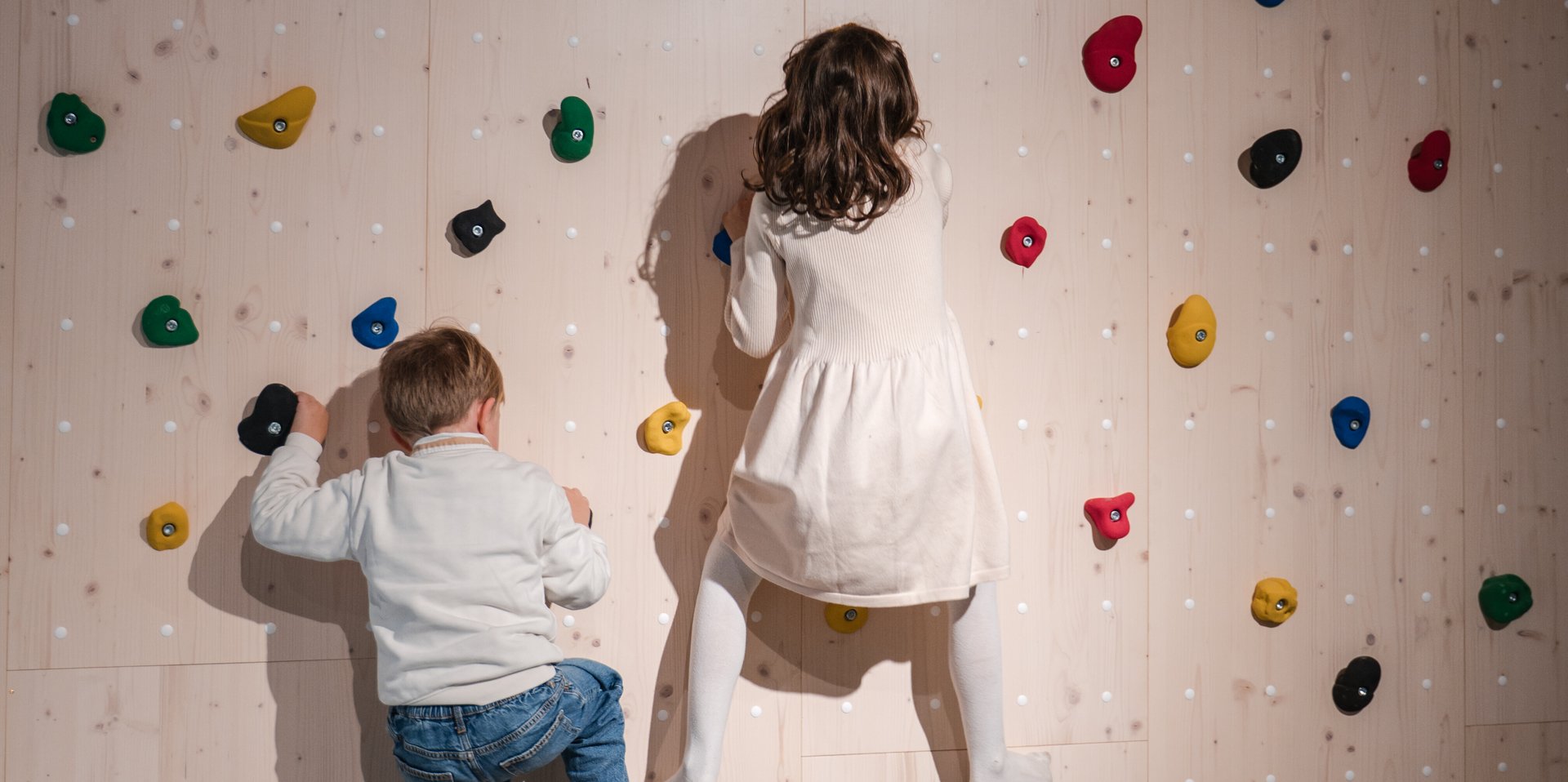 Zwei Kinder erklimmen gemeinsam die bunte Kletterwand in der Spielhalle des Hotels Vier Jahreszeiten am Schluchsee.