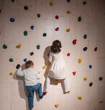 Zwei Kinder erklimmen gemeinsam die bunte Kletterwand in der Spielhalle des Hotels Vier Jahreszeiten am Schluchsee.