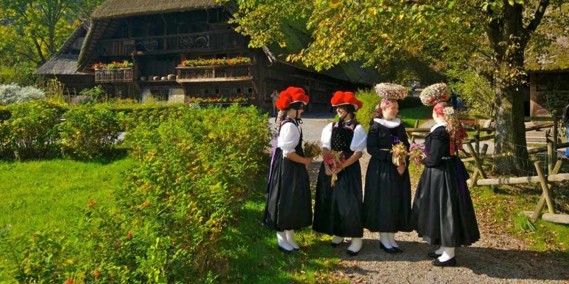 Personengruppe in Tracht vor einem alten Bauernhaus – Lebendige Geschichte.