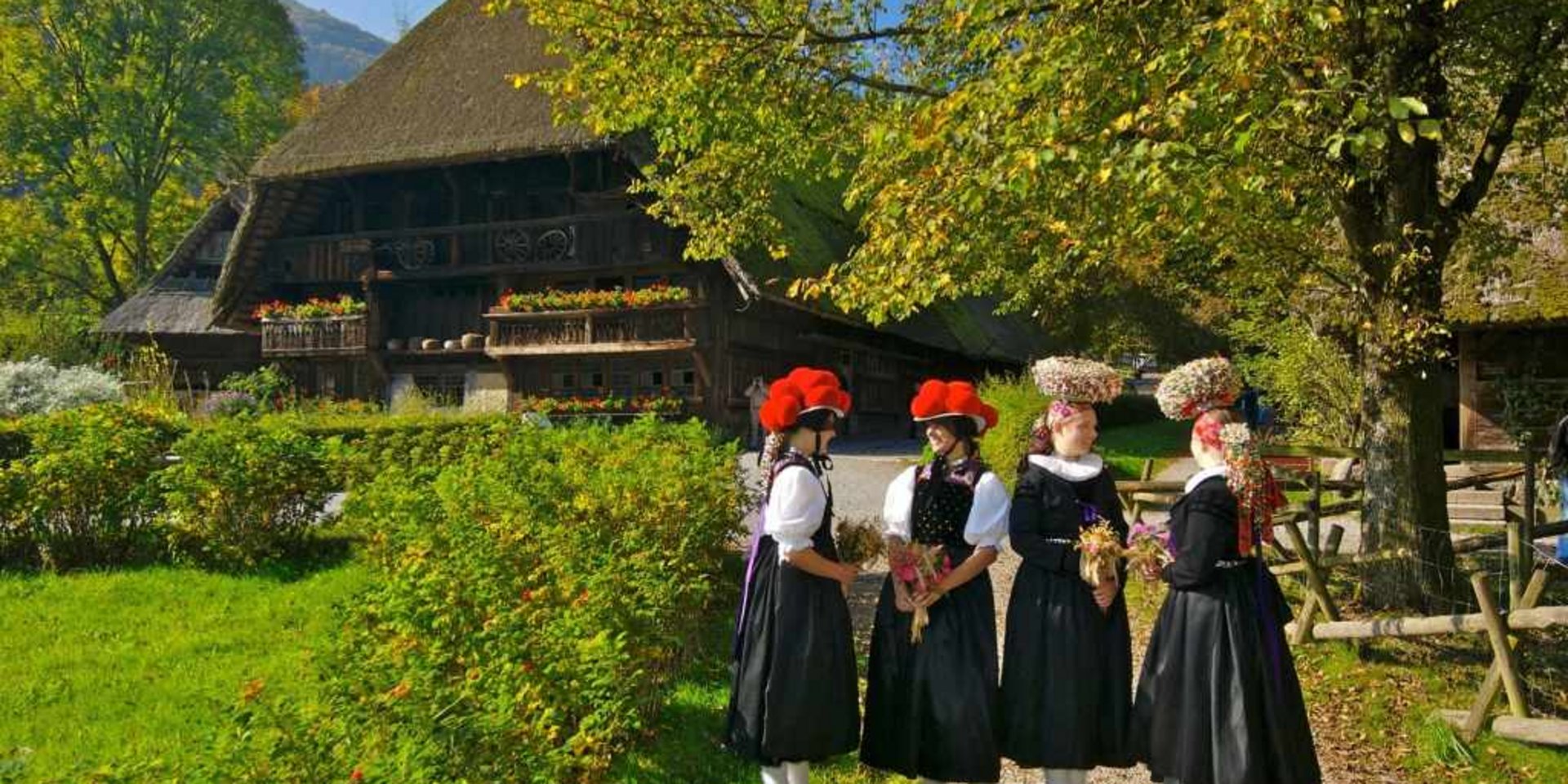 Personengruppe in Tracht vor einem alten Bauernhaus – Lebendige Geschichte.