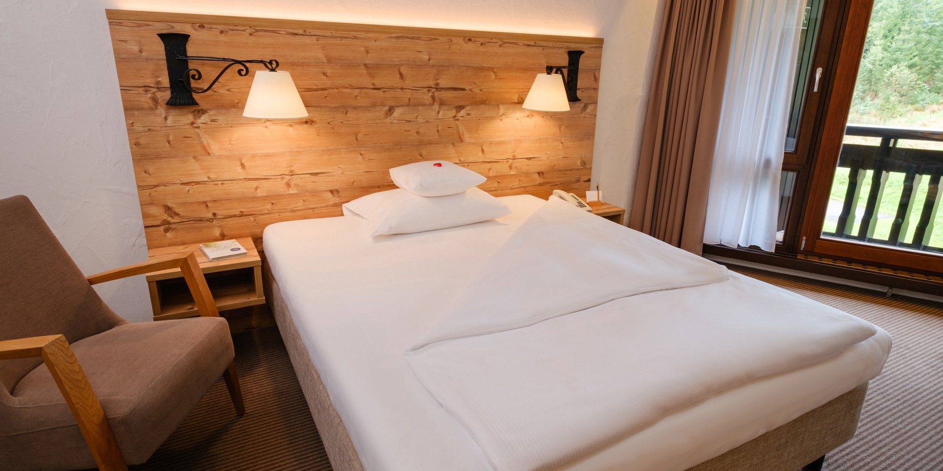 Komfortables Einzelbett mit Kopfteil aus Naturholz im Hotel Vier Jahreszeiten am Schluchsee.