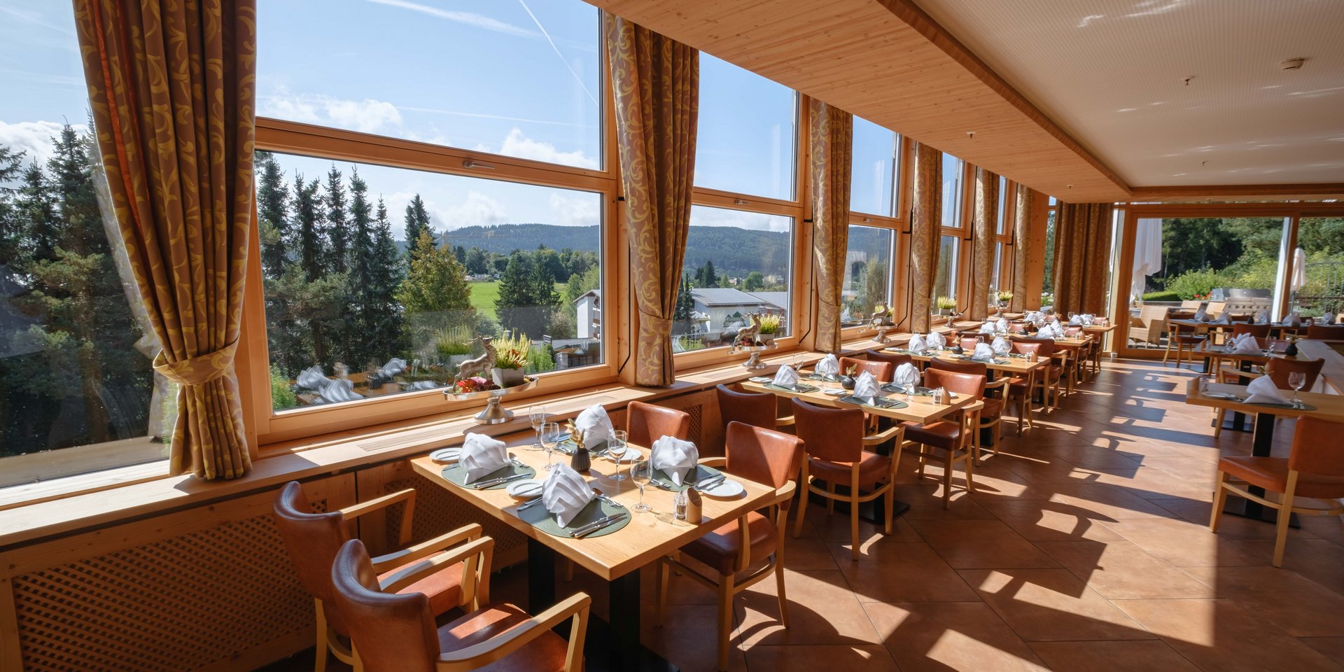 Lichtdurchfluteter Restaurantbereich mit eingedeckten Tischen und Blick auf den Schwarzwald im Hotel Vier Jahreszeiten am Schluchsee.