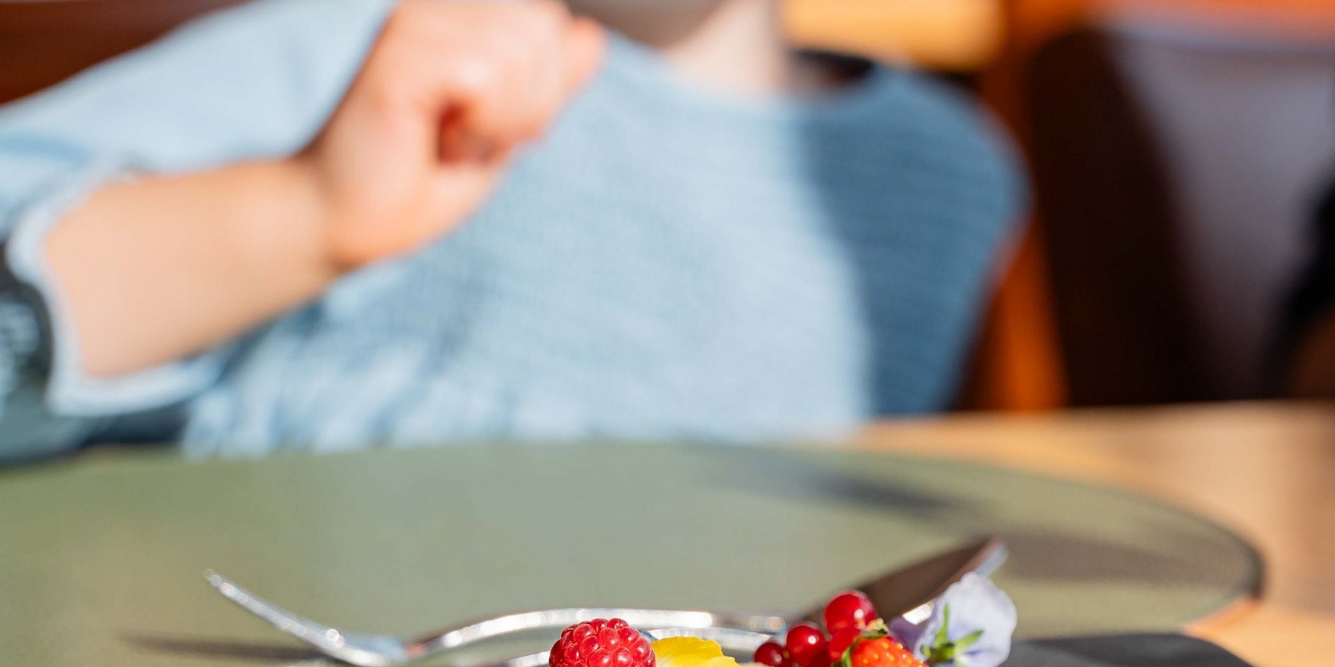 Ein lachendes Kind freut sich über ein liebevoll angerichtetes Dessert im Restaurant im Schwarzwald.