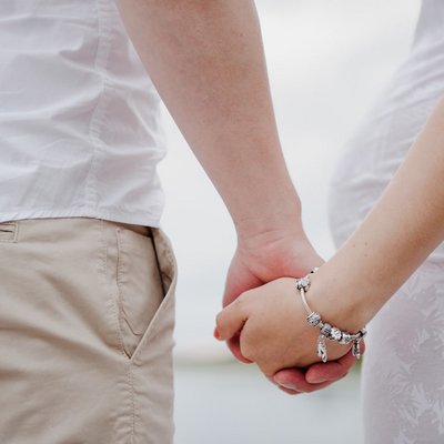 Ein Paar hält Händchen während eines entspannten Spaziergangs durch eine idyllische Parklandschaft.