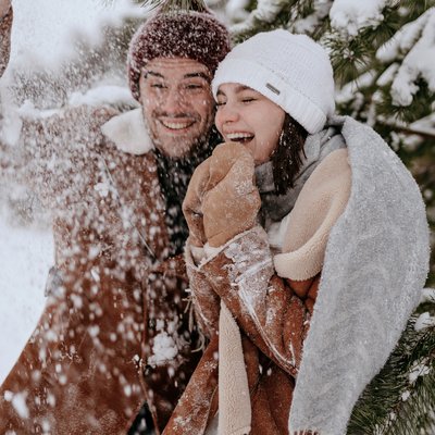 Paar unter einer Tanne von der Schnee fällt