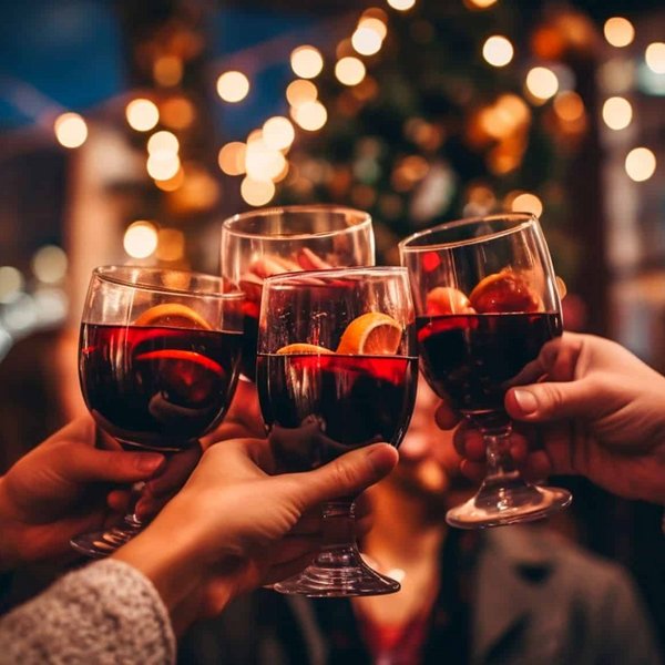 Eine Gruppe von Menschen stößt in einer gemütlichen, abendlichen Runde mit Gläsern an.