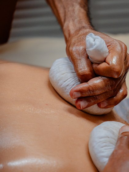 Durchführung einer traditionellen Ayurveda-Stempelmassage am Rücken eines Gastes im Hotel Vier Jahreszeiten im Schwarzwald.