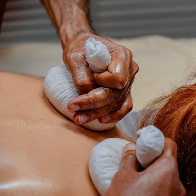 Durchführung einer traditionellen Ayurveda-Stempelmassage am Rücken eines Gastes im Hotel Vier Jahreszeiten im Schwarzwald.