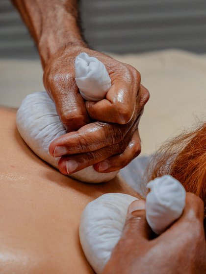 Durchführung einer traditionellen Ayurveda-Stempelmassage am Rücken eines Gastes im Hotel Vier Jahreszeiten im Schwarzwald.