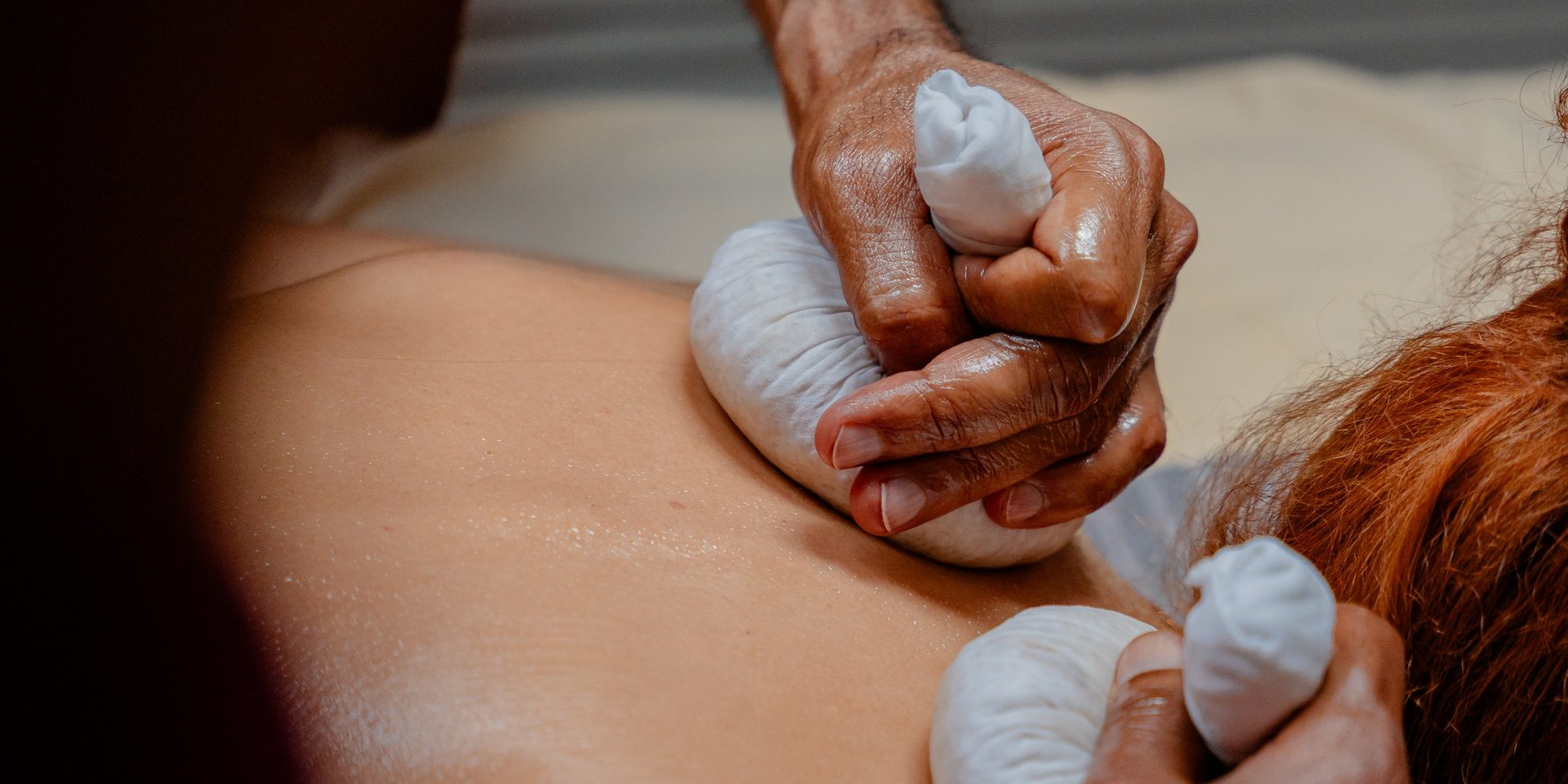 Durchführung einer traditionellen Ayurveda-Stempelmassage am Rücken eines Gastes im Hotel Vier Jahreszeiten im Schwarzwald.
