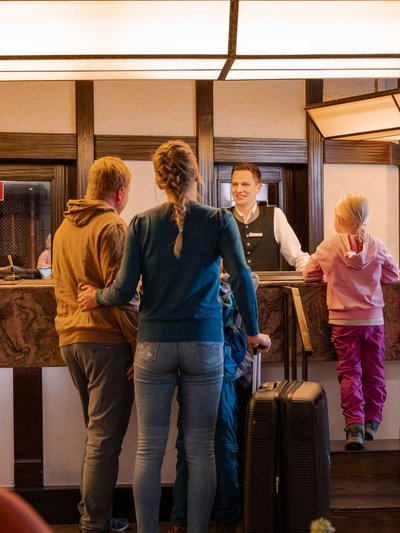 Gäste beim Check-in an der hölzernen Rezeption im Hotel Vier Jahreszeiten am Schluchsee.