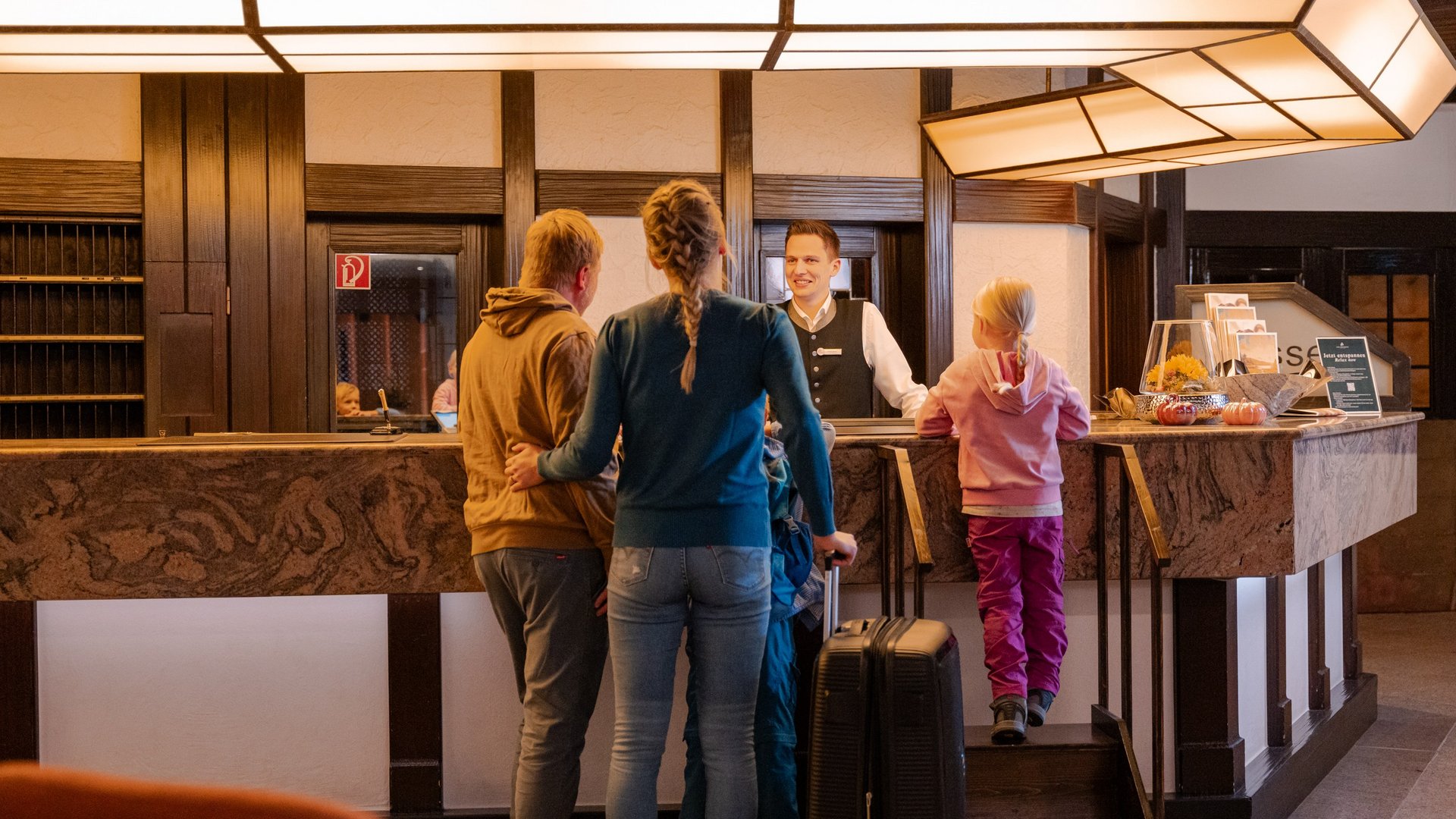 Gäste beim Check-in an der hölzernen Rezeption im Hotel Vier Jahreszeiten am Schluchsee.