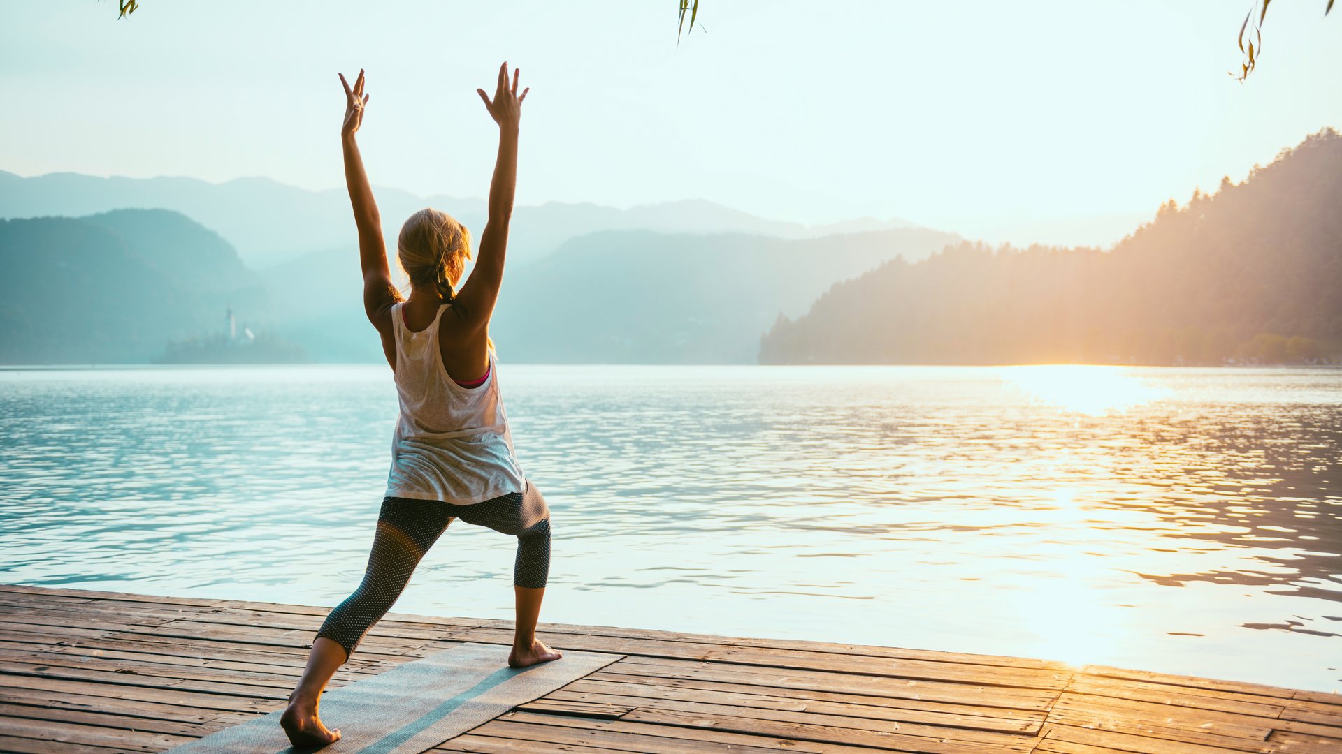 Frau beim Yoga am See beim Sonnenaufgang