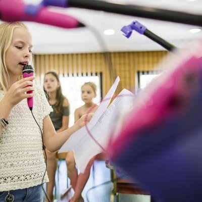 Eine Gruppe von Kindern spielt konzentriert mit Holzspielzeug in einem hellen Spielzimmer.
