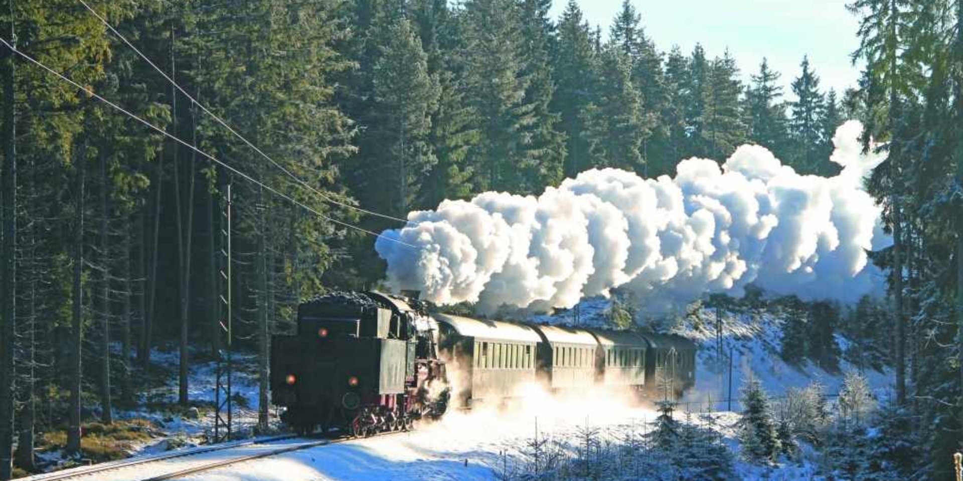 Blick auf eine verschneite Bahnstation im Schwarzwald während einer winterlichen Zugfahrt.