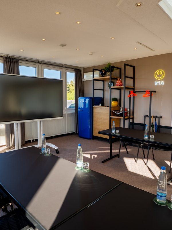Tagungsraum Seeblau mit Großbildschirm und Kühlschrank