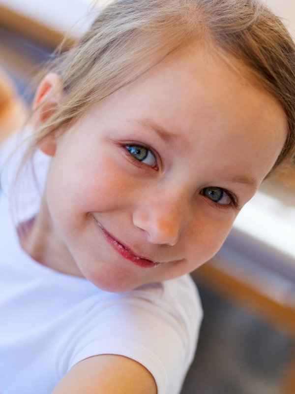 Porträt eines lächelnden kleinen Mädchens, das eine Gabel mit Nudeln hochhält.